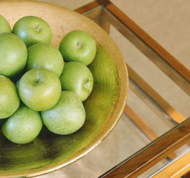 Grüne Äpfel liegen in einer goldenen Schale.